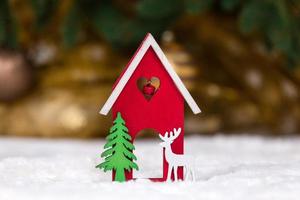 Christmas wooden toy house deer and tree on a white blanket imitating snow photo