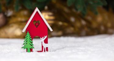 Christmas wooden toy house deer and tree on a white blanket imitating snow