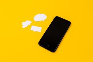 Smartphones with paper speech bubbles on yellow background photo