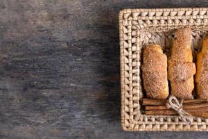 Croissants lie in a wicker basket with cinnamon