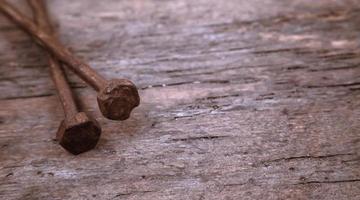 Two old rusty nails rest on a wooden background photo