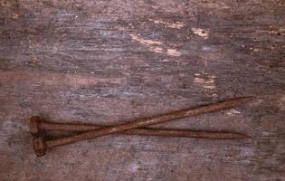 Two old rusty nails rest on a wooden background photo