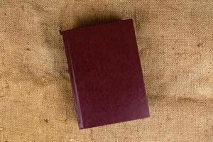 Una pila de libros antiguos sobre una textura de arpillera