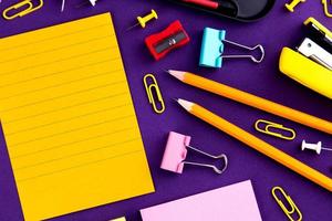 Material de oficina escolar papelería sobre un fondo púrpura escritorio con espacio para copiar concepto de regreso a la escuela foto