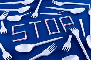 The word stop made of plastic tubes on a blue background with plastic utensils photo