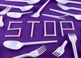 The word stop made of plastic tubes on a purple background with plastic utensils photo