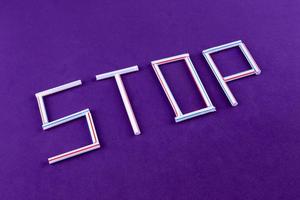 The word STOP made of plastic tubes on a purple background with empty space for text photo