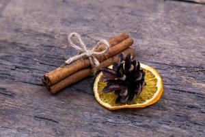 A pile of cinnamon sticks dried orange and cone on old wooden table photo