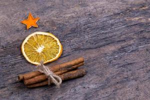 A pile of cinnamon sticks dried orange and tangerine stars on old wooden table in the form of a Christmas tree with copy space photo