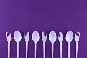 Plastic white spoons on purple background photo