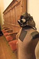 tailor doll with leather helmet and glasses stands in front of empty pews photo