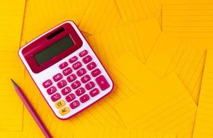 calculadora en hojas de papel naranja con lápiz foto