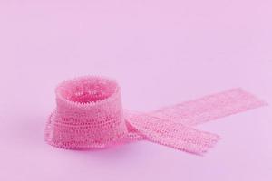 Lace ribbon neatly twisted into a ring on a pink background photo