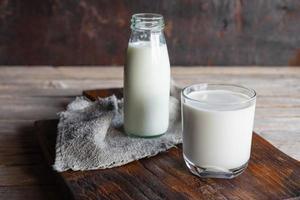 botellas y vasos de leche en una mesa de madera foto