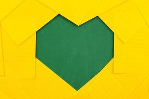 Orange sheets of paper on a green school board form a frame heart shape photo