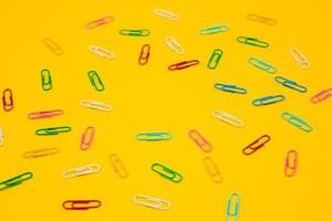 Colorful paper clips on yellow background photo