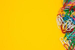 Colorful paper clips on yellow background photo