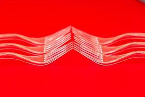 Close-up de horquillas de plástico transparente sobre un fondo rojo.