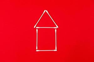 Cotton ear sticks arranged as a little house on red background photo