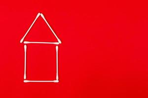 Cotton ear sticks arranged as a little house on red background photo