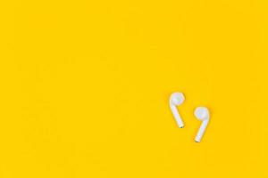 White earphones on yellow background with copy space