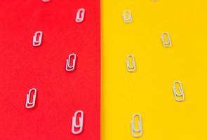 Close-up de clips de papel blanco sobre un fondo rojo y amarillo