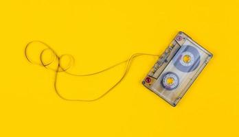 Top view of audio cassette with tangled tape on bright yellow background with copy space photo