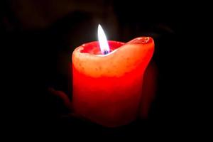 Female hands holding a burning candle in the darkness photo