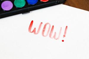 Handwritten WOW text with brush and watercolor paints on white background photo