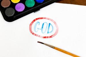 Handwritten GOD text with brush and watercolor paints on white background photo