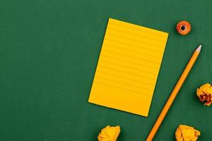 una hoja de papel naranja yace sobre una junta escolar verde foto