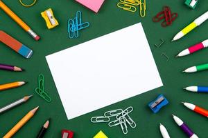 School stationery lies on a green school board forming a frame for text photo