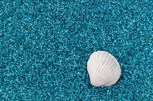 conchas marinas blancas dispuestas sobre un moderno fondo de brillo azul agua foto