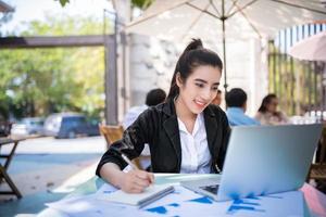 Busy young businesswoman working on a desk using a laptop in a coffee shop photo