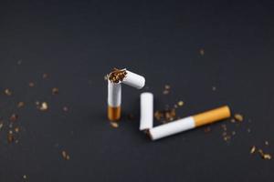 Breaking destroying cigarettes smoking tobacco flat lay on black grunge texture background for any smoking concepts like World No Tobacco Day or WNTD on 31 May or the dangers of using tobacco ideas photo