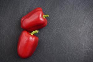 Closeup colorful fancy red bell or sweet peppers flat lay on grunge scratched texture black background photo