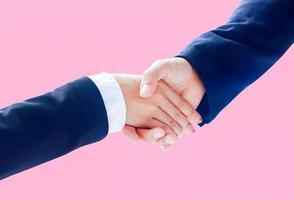 Businesspeople shaking hands on a pink background photo