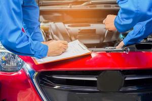 Mechanic in the car service department is checking the condition of the engine and vehicle chassis photo