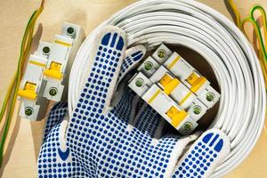 gloves of the electrician lie on the coil with wires and circuit breakers set of electrician for connecting electricity in the house photo