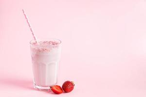 Fresh milkshake with strawberries on pink background photo