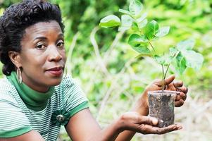 Mujer joven con una flor plantada en un tazón. foto