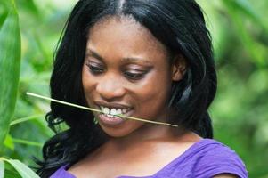 Mujer sonriente con una brizna de hierba en la boca foto