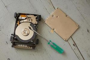 Broken and Destroyed Hard Drive Disk and Tools on Wooden Table photo