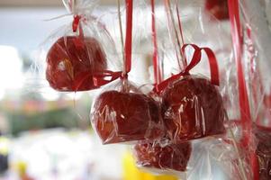 Lots of appetizing red candied apples hanging outdoors