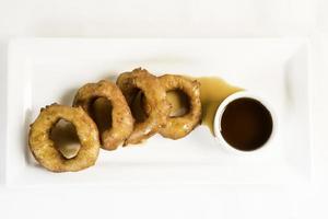 Picarones These are ring shaped dessert made with wheat flour dough mixed with pumpkin and sweet potato fried and dipped in fig molasses photo