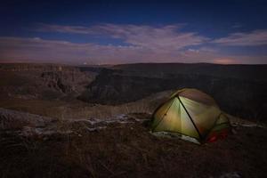 Green tent illuminated on grass surface photo