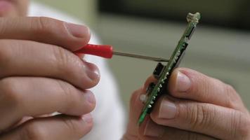 un technicien examine un microcircuit, gros plan sur ses mains