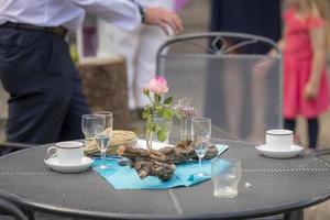 After the party  flowers decoration with used glasses and plates stands on a patio table photo