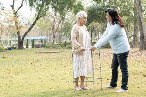 Ayude y cuide a la anciana asiática mayor o anciana que use un andador con una salud fuerte mientras camina en el parque en felices vacaciones frescas