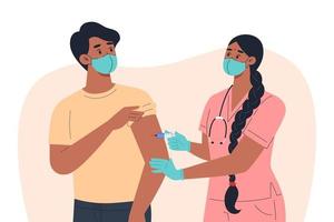 A nurse in a mask and gloves makes a vaccine to a male patient